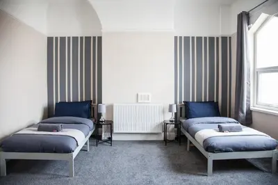 a room with two beds and a radiator at Spacious House 10min to Liverpool Centre in Wallasey