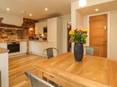 a kitchen with a wooden table with a vase of flowers at Woodman Cottage in Morecambe