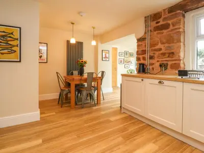 a kitchen and dining room with a wooden table at Woodman Cottage in Morecambe