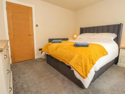 a bedroom with a large bed with a yellow blanket at Woodman Cottage in Morecambe