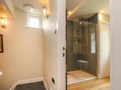 a bathroom with a shower with a glass door at Woodman Cottage in Morecambe