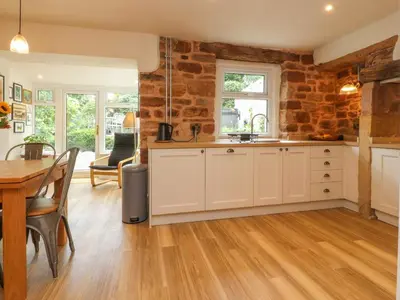a kitchen with a table and a dining room at Woodman Cottage in Morecambe