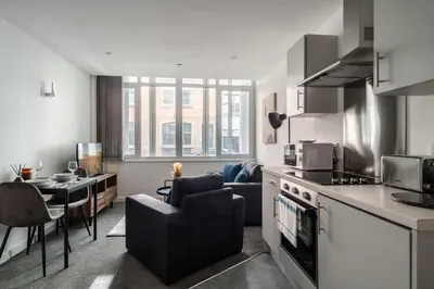 a kitchen and living room with a couch and a table at Central Preston Modern 1 Bedroom Apartment in Preston