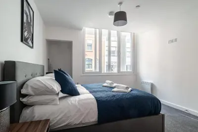 a bedroom with a bed with a blue blanket and a window at Central Preston Modern 1 Bedroom Apartment in Preston
