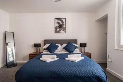 a bedroom with a large blue bed with blue pillows at Central Preston Modern 1 Bedroom Apartment in Preston