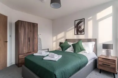 a bedroom with a green bed with towels on it at 1 Bed Modern Central Preston Apartment in Preston