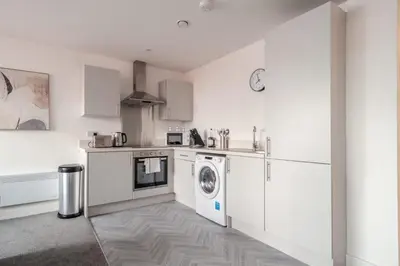 a kitchen with white cabinets and a washer and dryer at 1 Bed Modern Central Preston Apartment in Preston