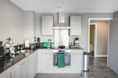 a kitchen with white cabinets and a green towel at Waterfront Luxury Apartment in Liverpool