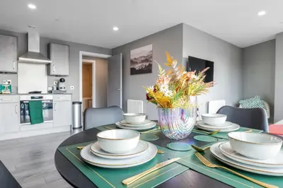 a dining room table with a vase of flowers on it at Waterfront Luxury Apartment in Liverpool