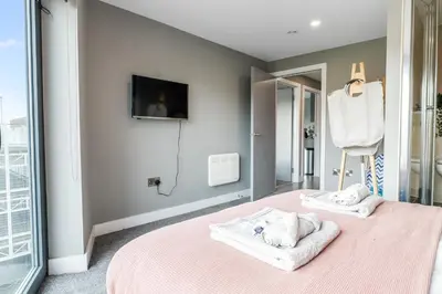 a bedroom with a pink bed with towels on it at Waterfront Luxury Apartment in Liverpool