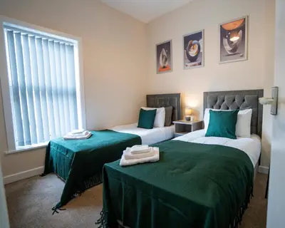 a bedroom with two beds with green sheets and a window at Miles Home Anfield-Liverpool in Liverpool