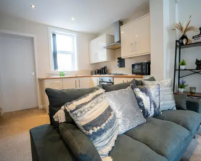 a living room with a green couch and a kitchen at Miles Home Anfield-Liverpool in Liverpool