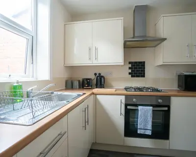 a kitchen with white cabinets and a sink at Miles Home Anfield-Liverpool in Liverpool