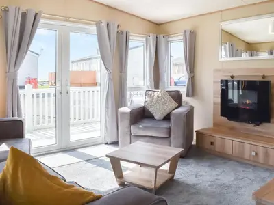 a living room with a television and a chair and a table at Peachy in Heysham