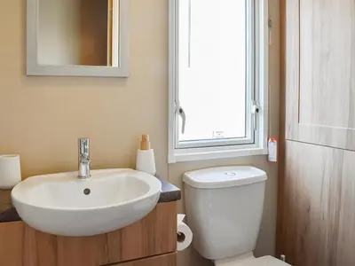 a bathroom with a sink and a toilet and a window at Peachy in Heysham