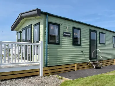 a green tiny house with a white railing at Peachy in Heysham