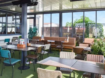a restaurant with tables and chairs and windows at Peachy in Heysham