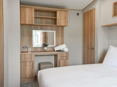 a bedroom with a bed and a desk and a mirror at Peachy in Heysham