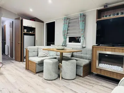 a living room with a couch and a table and a television at Vinchella-3 bedroom caravan in Grange Over Sands