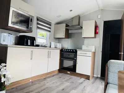 a small kitchen with white cabinets and a microwave at Vinchella-3 bedroom caravan in Grange Over Sands