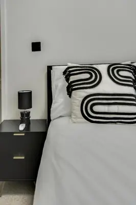 a bed with a black and white pillow and a nightstand at Ripon By Serene Stays Stylish Liverpool Home Sleeps 5 with Free Parking Fast WiFi and Close to Stadiums in Liverpool