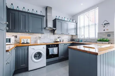 a kitchen with blue cabinets and a washing machine at Trent House - Quality 3 Bedroom House Lytham in Brown Moss Side