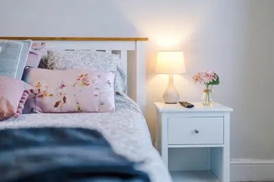 a bed with a pink pillow and a nightstand with a lamp at Trent House - Quality 3 Bedroom House Lytham in Brown Moss Side