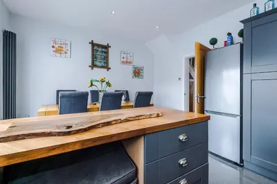 a kitchen with a wooden counter with chairs and a refrigerator at Trent House - Quality 3 Bedroom House Lytham in Brown Moss Side