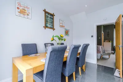 a dining room with a wooden table and blue chairs at Trent House - Quality 3 Bedroom House Lytham in Brown Moss Side