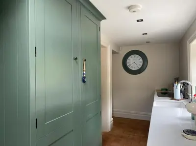 a green door in a kitchen with a clock on the wall at The Bothy Cottage in Lytham St Annes
