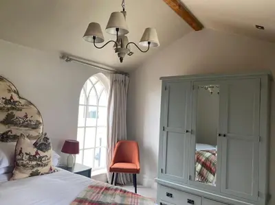 a bedroom with a bed and a chair and a chandelier at The Bothy Cottage in Lytham St Annes