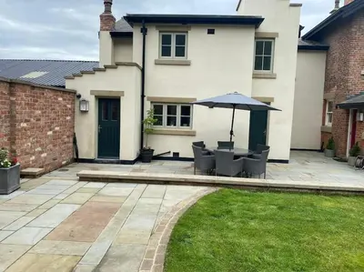 a patio with chairs and an umbrella in front of a house at The Bothy Cottage in Lytham St Annes