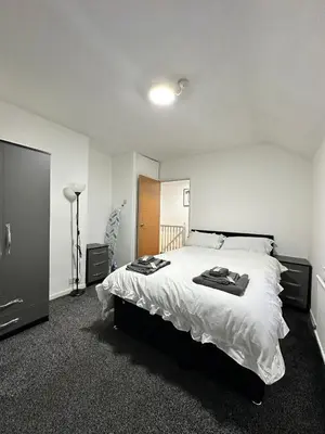 a bedroom with a large bed with white sheets at Cozy 3-Bedroom House in Bolton, Huge Garden in Egerton