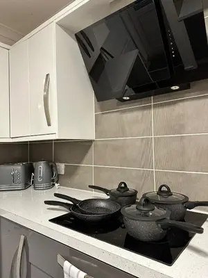 a kitchen with four pots and pans on a stove at Cozy 3-Bedroom House in Bolton, Huge Garden in Egerton
