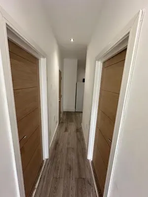 an empty hallway with two closet doors and a refrigerator at Luxury rooms Liverpool in Seacombe