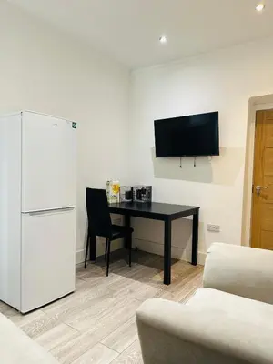a room with a desk and a refrigerator and a table at Luxury rooms Liverpool in Seacombe