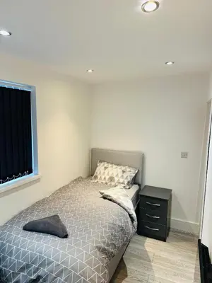 a bedroom with a bed and a black dresser at Luxury rooms Liverpool in Seacombe
