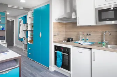a kitchen with white cabinets and blue accents at Studio In Central Liverpool, Free Breakfast in Liverpool