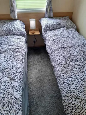 two beds in a bedroom with a nightstand between them at Escape to the bay- arnside escapes in Morecambe