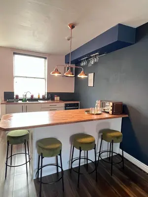 a kitchen with a counter with stools around it at Ropewalks City Centre Apartment with Roof Terrace in Liverpool