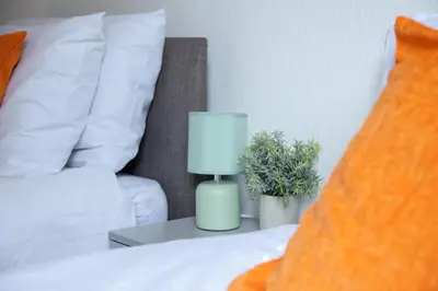 a bed with a lamp on a table next to a couch at Spacious 2-Bedroom Flat with 4 Beds, Ideal for Contractors, Long Stay Deals in Wallasey
