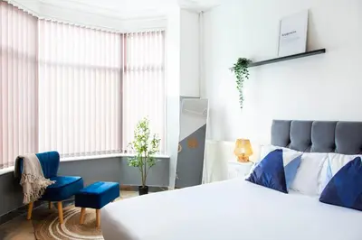 a bedroom with a white bed and a blue chair at Eco-Friendly Stay in Barrow-In-Furness, Lake District in Barrow in Furness