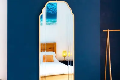 a mirror in a room with a bed and a blue wall at Eco-Friendly Stay in Barrow-In-Furness, Lake District in Barrow in Furness