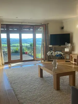 a living room with a table and a large sliding glass door at The View in Oswaldtwistle