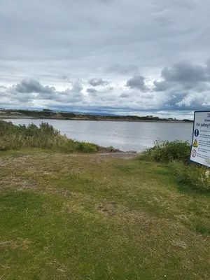 a sign in the grass next to a body of water at Angie stunning holiday home in Heysham