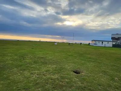 a large grass field with horses in the distance at Angie stunning holiday home in Heysham
