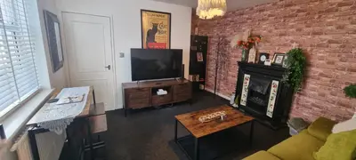 a living room with a television and a brick wall at The Hideaway Cottage Feel Patio Central Parking in Southport