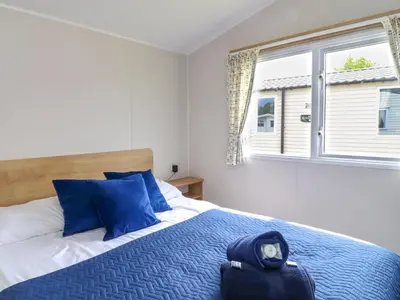 a bedroom with a bed with blue pillows and a window at Windermere Lodge in Morecambe