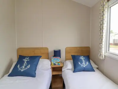 two beds with blue pillows in a room at Windermere Lodge in Morecambe
