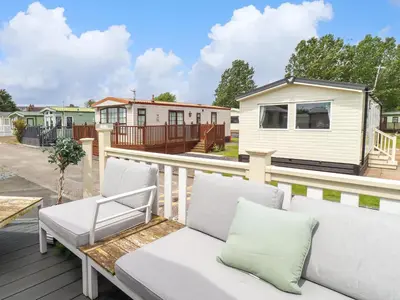 a white bench on a deck with a house at Windermere Lodge in Morecambe